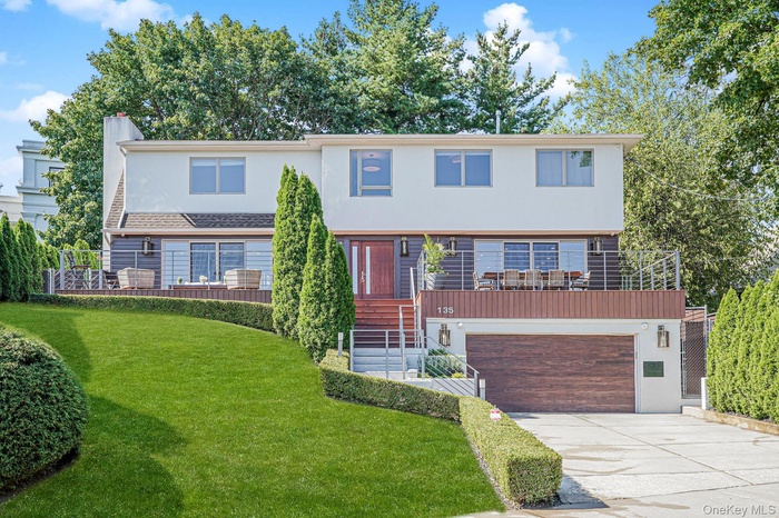 View of front of home featuring stucco siding, driveway, a front yard, a garage, and stairs