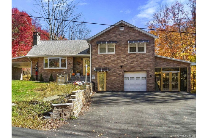 View of front facade featuring asphalt driveway, a garage, and a chimney