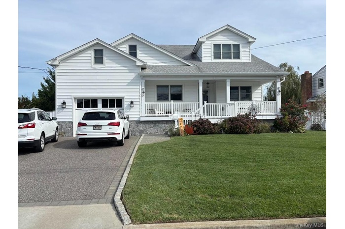 View of front facade featuring a shingled roof, a front yard, asphalt driveway, and a porch