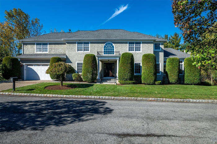 View of front of house with driveway, a front lawn, an attached garage, and roof with shingles