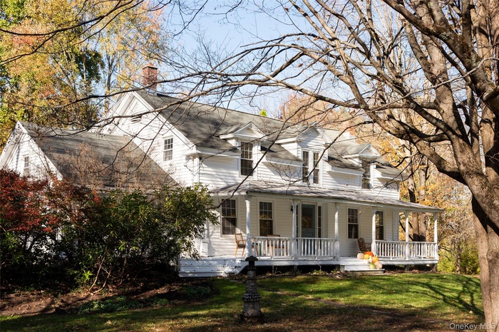 View of front of property featuring a chimney, a porch, and a front lawn