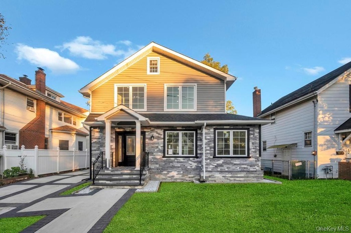 View of front of house with stone siding and roof with shingles