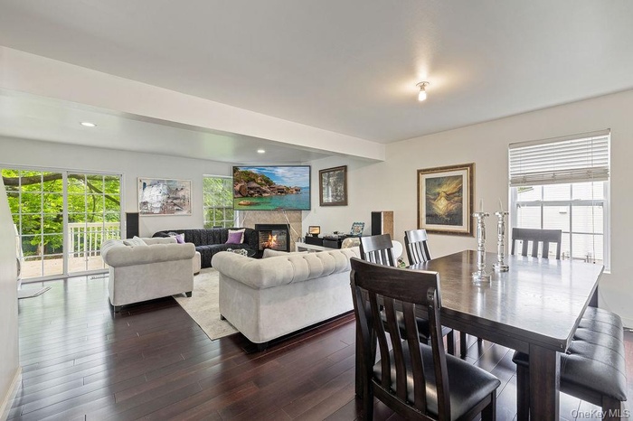 Dining room featuring a glass covered fireplace, healthy amount of natural light, dark wood-style floors, and recessed lighting