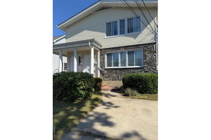 View of front of house featuring stone siding and covered porch