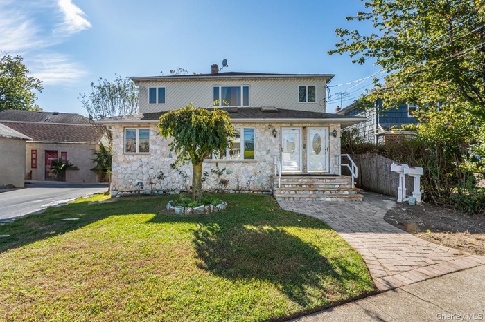 View of front of property with a front lawn and stone siding