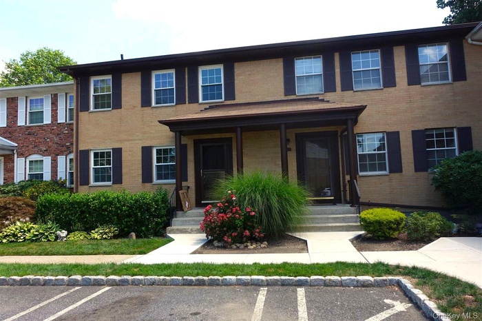 Colonial house with brick siding and uncovered parking