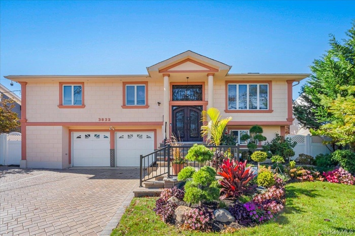 Split foyer home with decorative driveway, an attached garage, and a balcony
