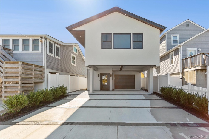 View of front of property featuring stucco siding, concrete driveway, and a residential view