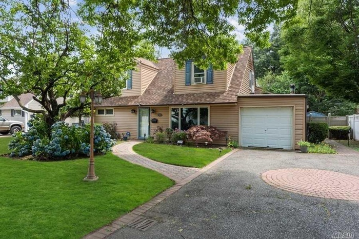 View of front of house with asphalt driveway, a garage, and roof with shingles