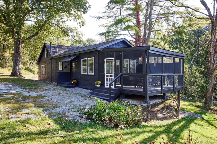Back of property with a sunroom, a deck, and a lawn