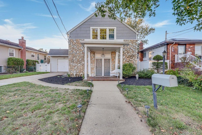 View of front of home featuring stone siding, driveway, and a garage