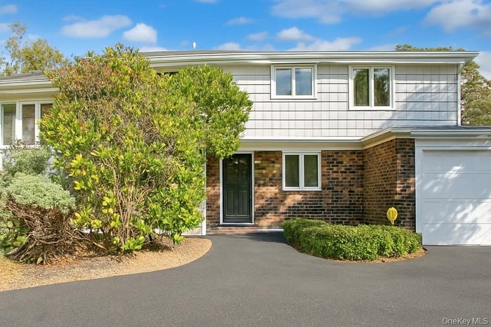 View of front of house featuring brick siding, a garage, and asphalt driveway