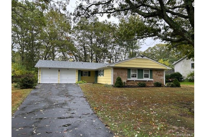 Ranch-style house featuring a garage, asphalt driveway, and a front yard
