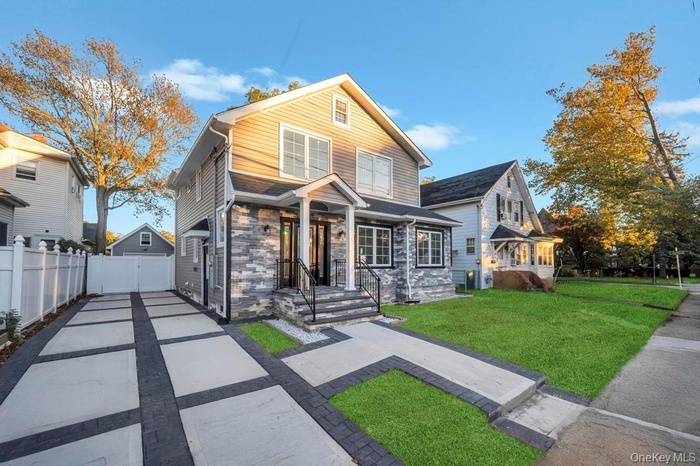 View of front facade with stone siding and driveway