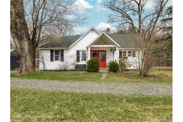 View of front facade featuring a chimney, a front lawn, and roof with shingles