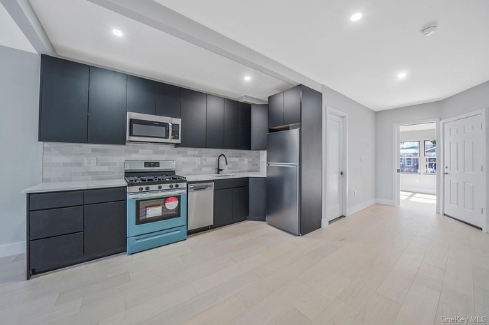 Kitchen featuring appliances with stainless steel finishes, backsplash, modern cabinets, light wood finished floors, and recessed lighting