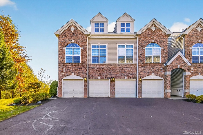 Traditional-style house with a garage, driveway, and brick siding