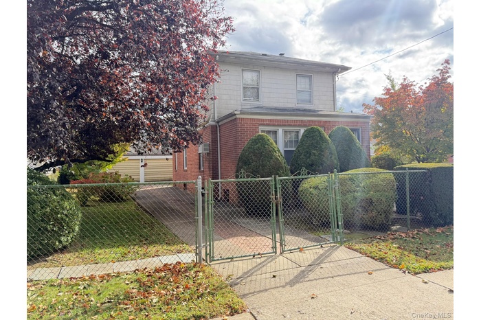 Traditional-style house with a gate, a fenced front yard, and brick siding