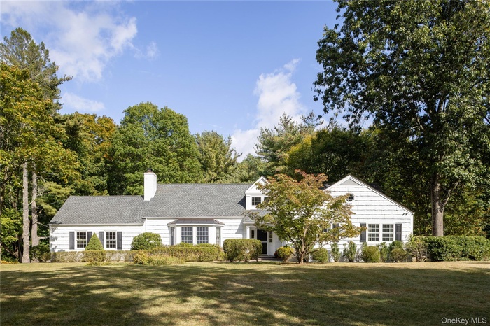 View of front of property with a front lawn, a chimney, and roof with shingles