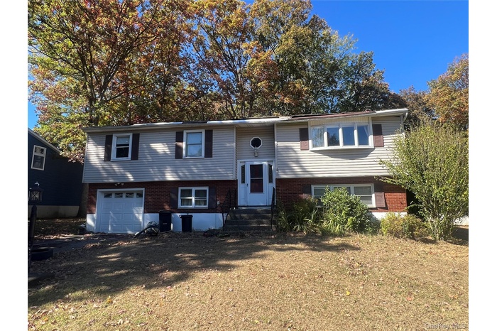 Bi-level home with brick siding, a garage, and driveway