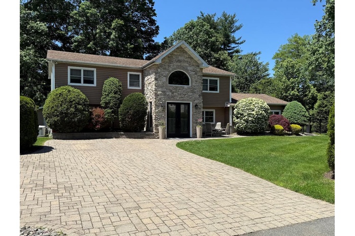 View of front of house featuring french doors, a front yard, stone siding, and driveway