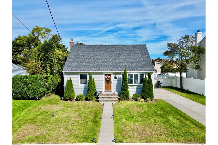 New england style home featuring roof with shingles and a chimney