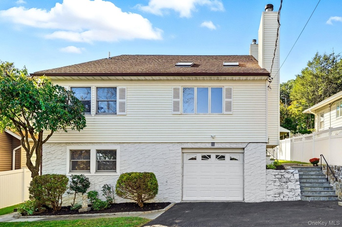 View of front of house featuring a garage, a shingled roof, a chimney, and asphalt driveway