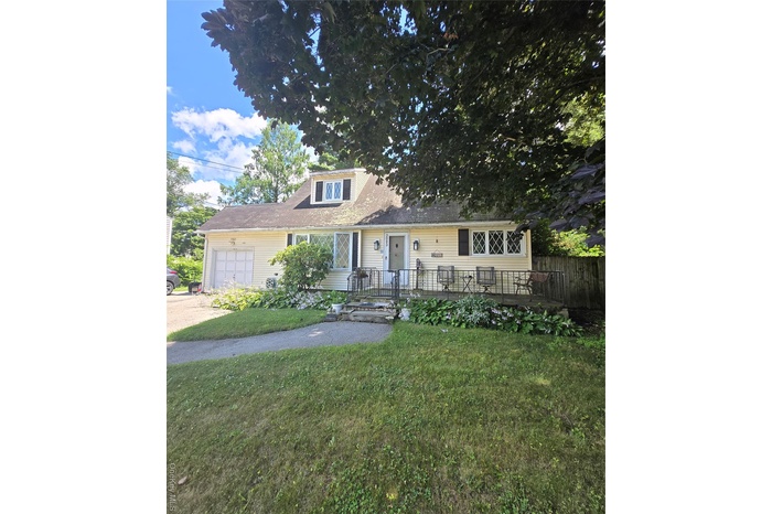 View of front facade featuring a front yard, a garage, and driveway