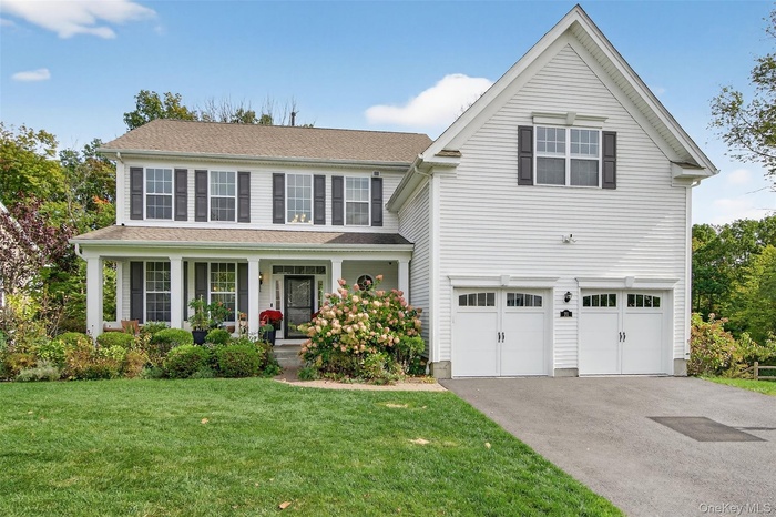 View of front of house with covered porch, a front yard, asphalt driveway, and roof with shingles