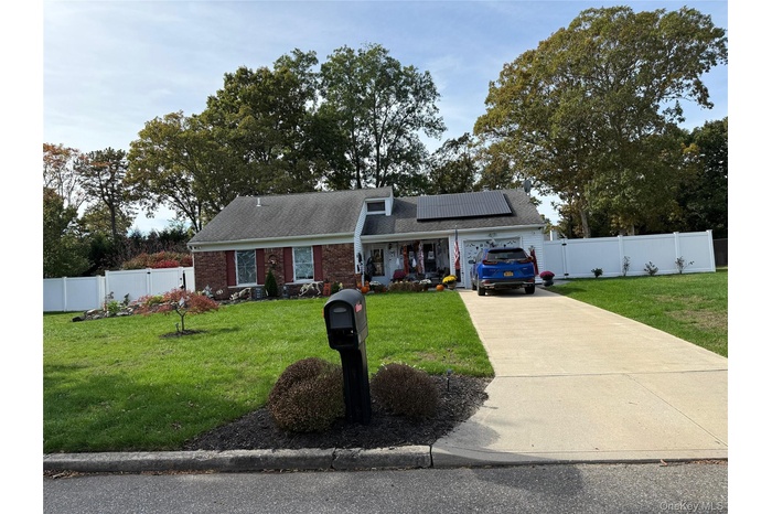 View of front of house featuring roof mounted solar panels, driveway, roof with shingles, brick siding, and a garage