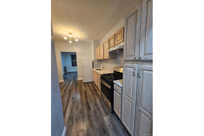 Kitchen featuring gas stove, freestanding refrigerator, tasteful backsplash, light countertops, and dark wood-type flooring