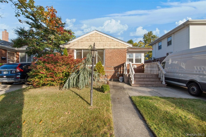 Bungalow-style home featuring brick siding, a front lawn, and a deck