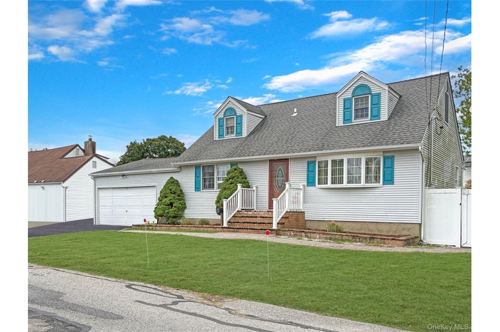 New england style home with roof with shingles, asphalt driveway, and a garage
