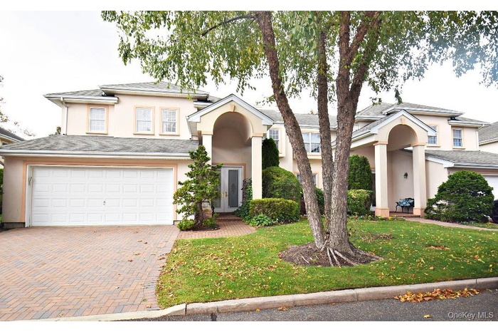 View of front of home featuring stucco siding, a front lawn, decorative driveway, and a garage