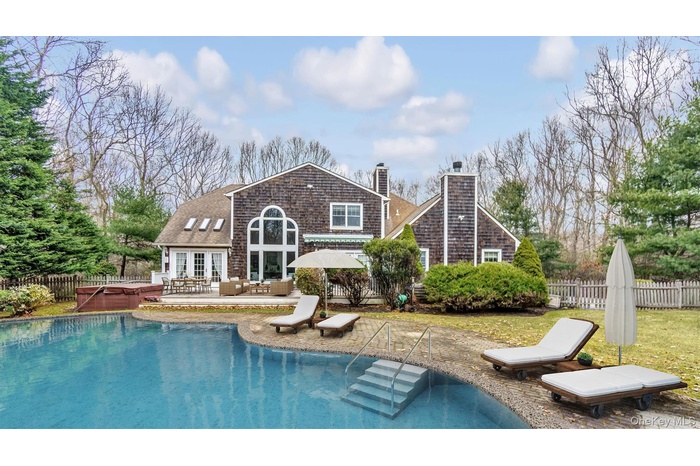 Rear view of property featuring a fenced backyard, french doors, a fenced in pool, a chimney, and a hot tub