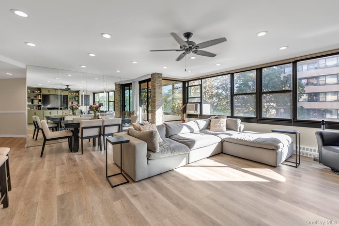 Living room with a ceiling fan, light wood-style flooring, and recessed lighting