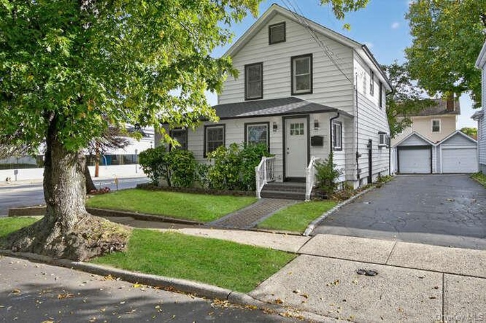 View of front of home with a garage, an outbuilding, and a front lawn