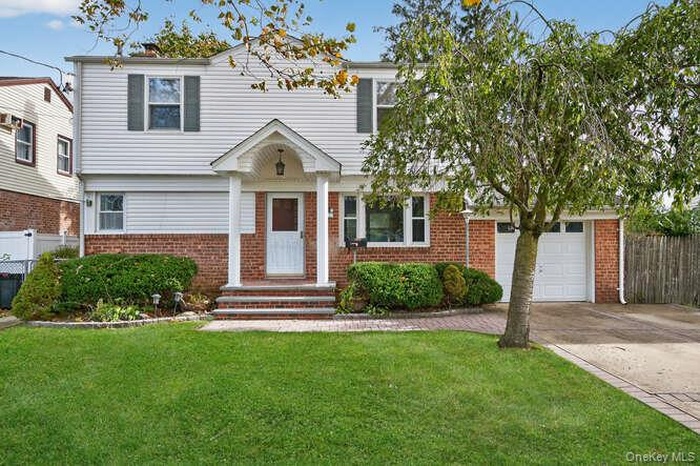 View of front of home featuring brick siding, driveway, and a garage