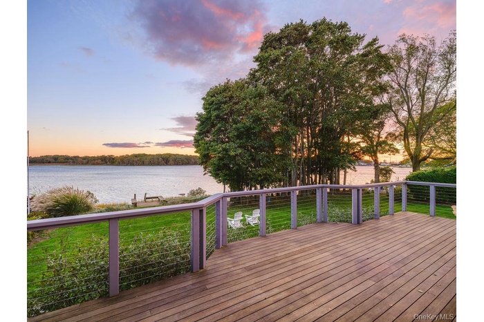 Deck at dusk with a water view and a yard