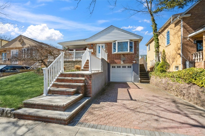 View of front of home featuring stairs, a front lawn, a garage, decorative driveway, and brick siding
