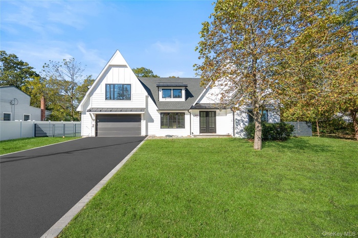 Modern inspired farmhouse with board and batten siding, driveway, a shingled roof, and a garage