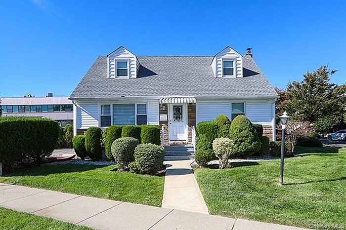 Cape cod-style house featuring a front lawn and roof with shingles