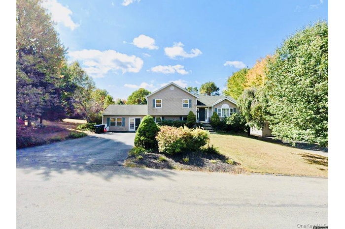 Tri-level home with asphalt driveway and a front yard