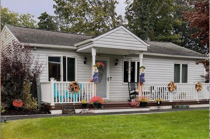 Bungalow with covered porch, a shingled roof, and a front yard