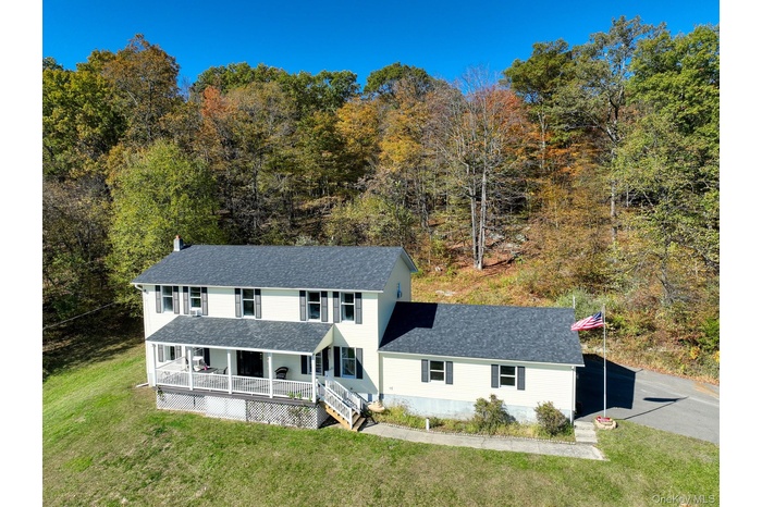 View of front of property with a porch, a shingled roof, and a front yard