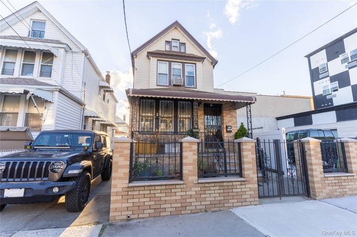 View of front facade with a fenced front yard, a gate, and brick siding