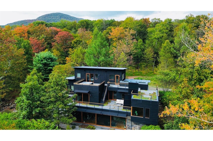 Rear view of house featuring a balcony and a forest view