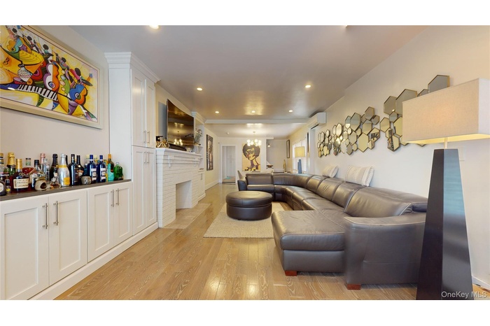 Living room with light wood-style flooring, recessed lighting, a brick fireplace, an AC wall unit, and a chandelier