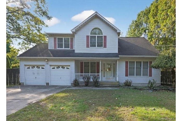 Traditional-style home featuring covered porch, driveway, and a chimney
