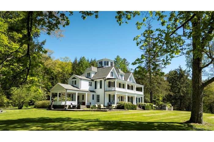 Rear view of house with a balcony, a lawn, a patio area, and view of wooded area